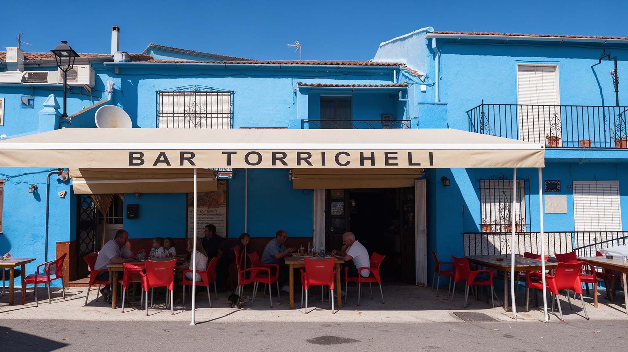 Fachada azul del Bar Torricheli con terraza y toldo en Júzcar